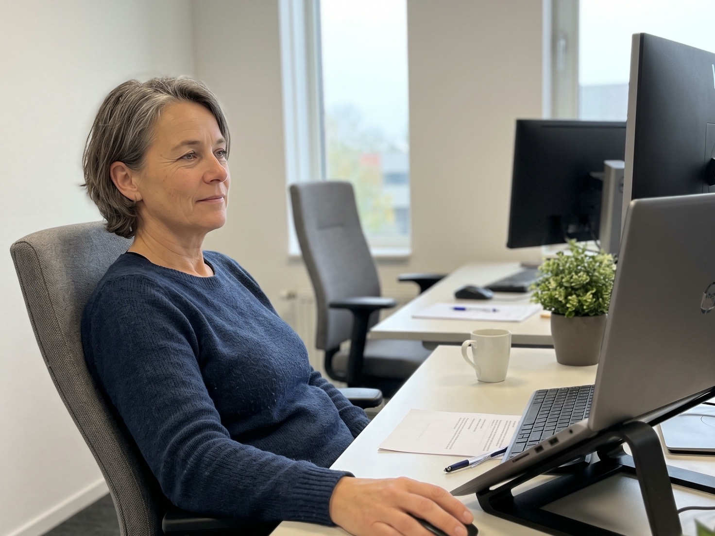 Financieel adviseur achter haar bureau in een rustig advieskantoor, met een lege werkplek op de achtergrond