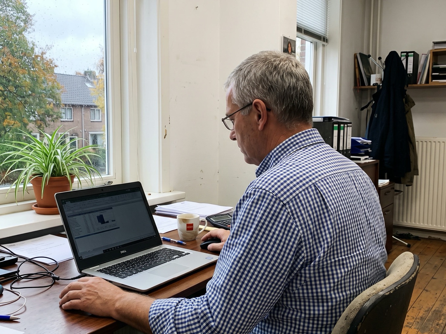 Financieel adviseur werkt geconcentreerd achter zijn laptop in een rustig advieskantoor, gezien over de schouder