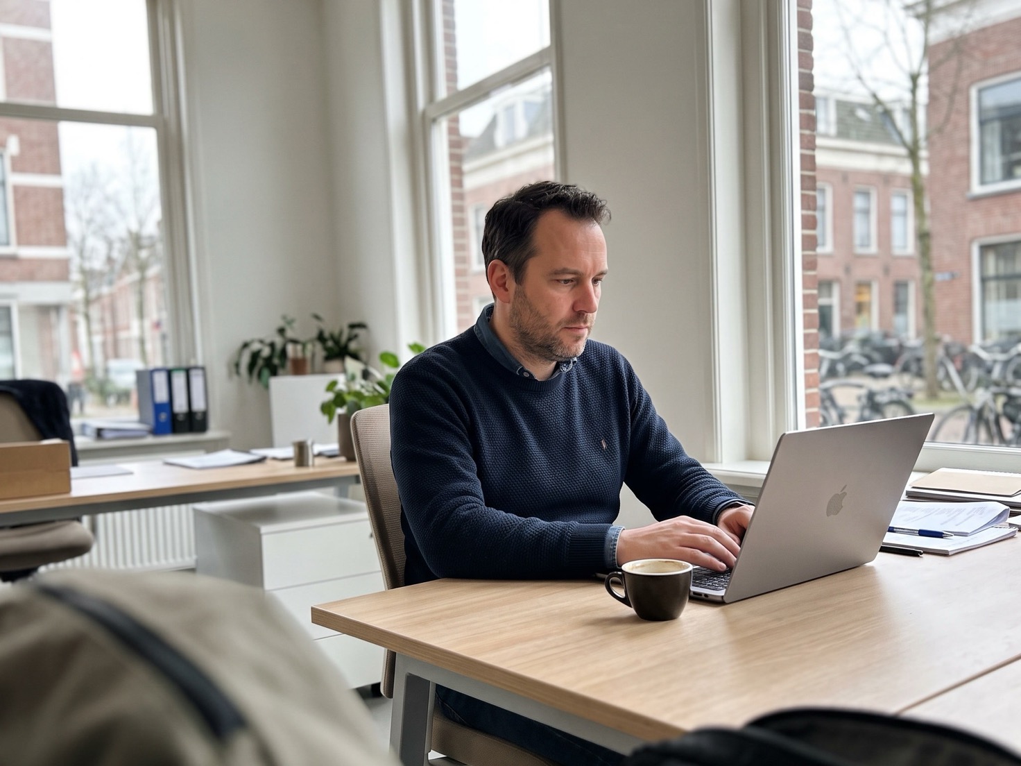 Financieel adviseur werkt geconcentreerd achter zijn bureau in een rustig kantoor