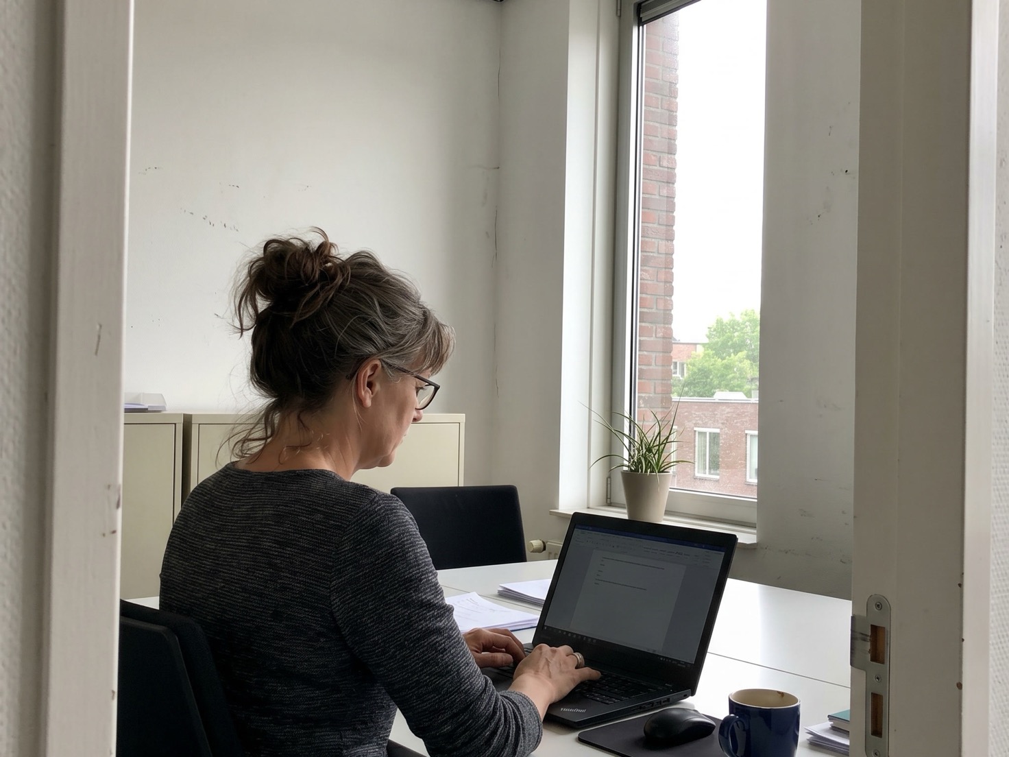 Adviseur werkt achter een laptop in een rustig advieskantoor