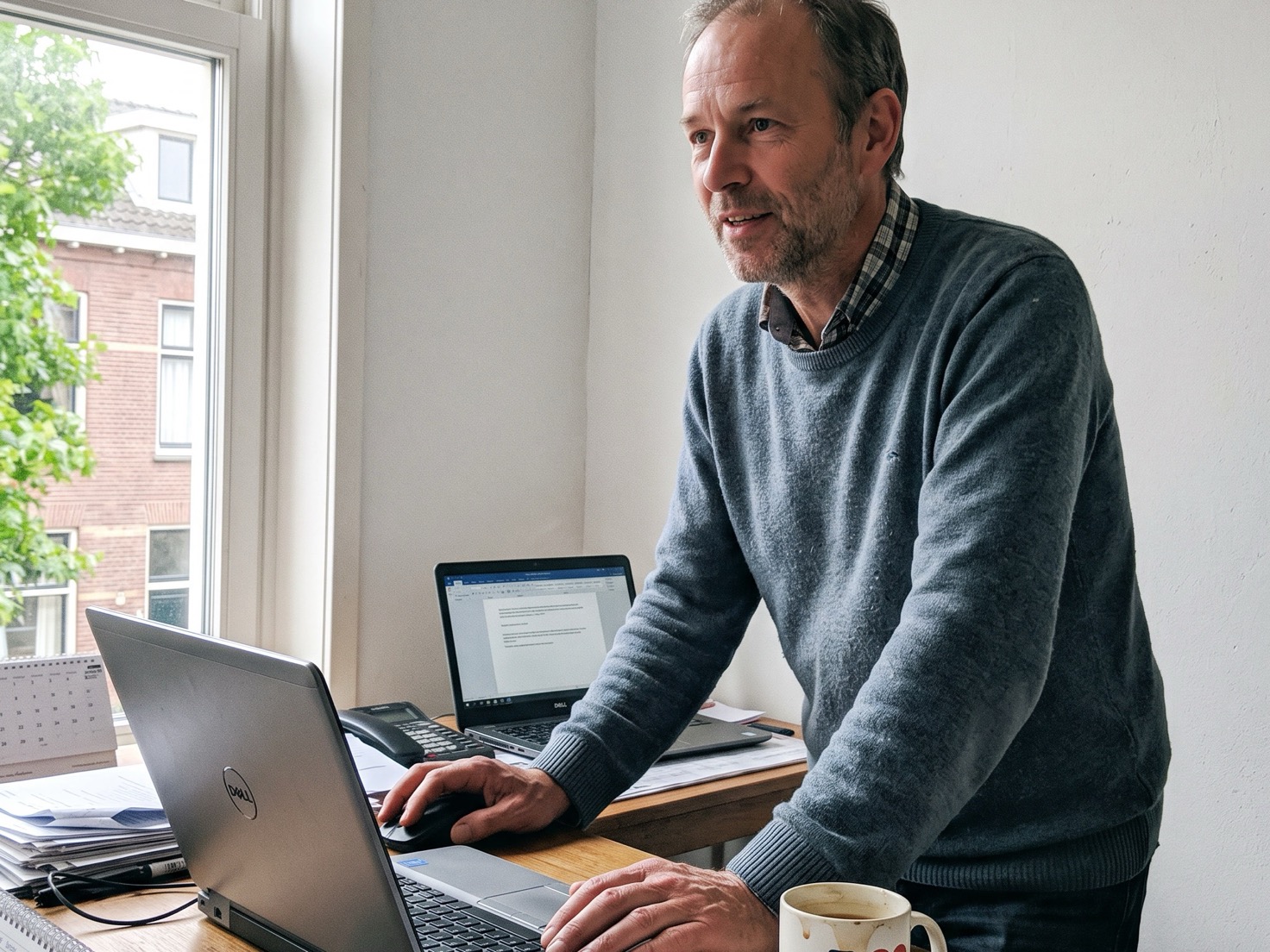 Adviseur staat naast zijn bureau en werkt aan een laptop in een rustig kantoor