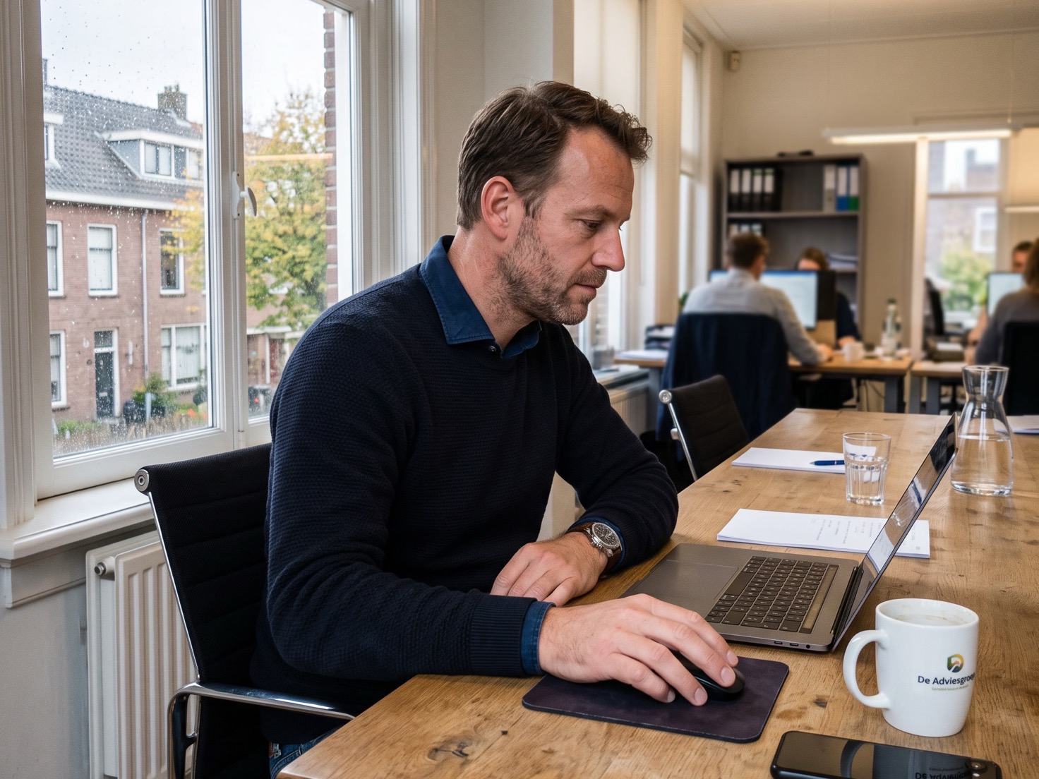 Financieel adviseur werkt achter een laptop aan de overlegtafel van een advieskantoor