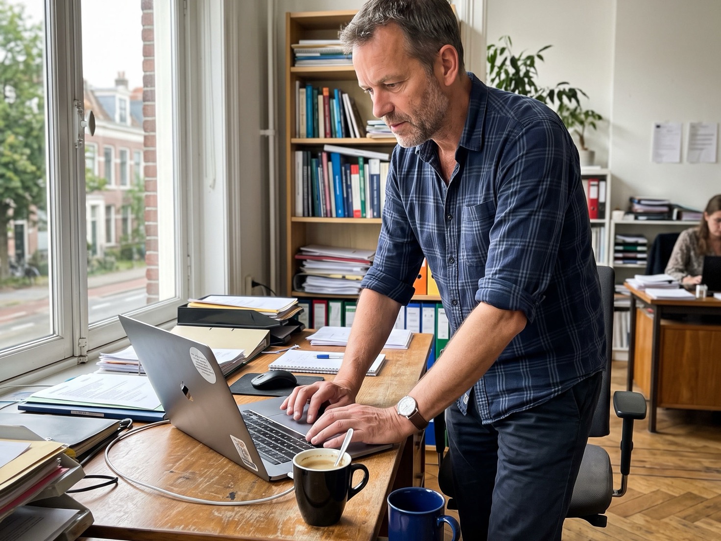 Financieel adviseur werkt naast zijn bureau op een laptop in een rustig advieskantoor