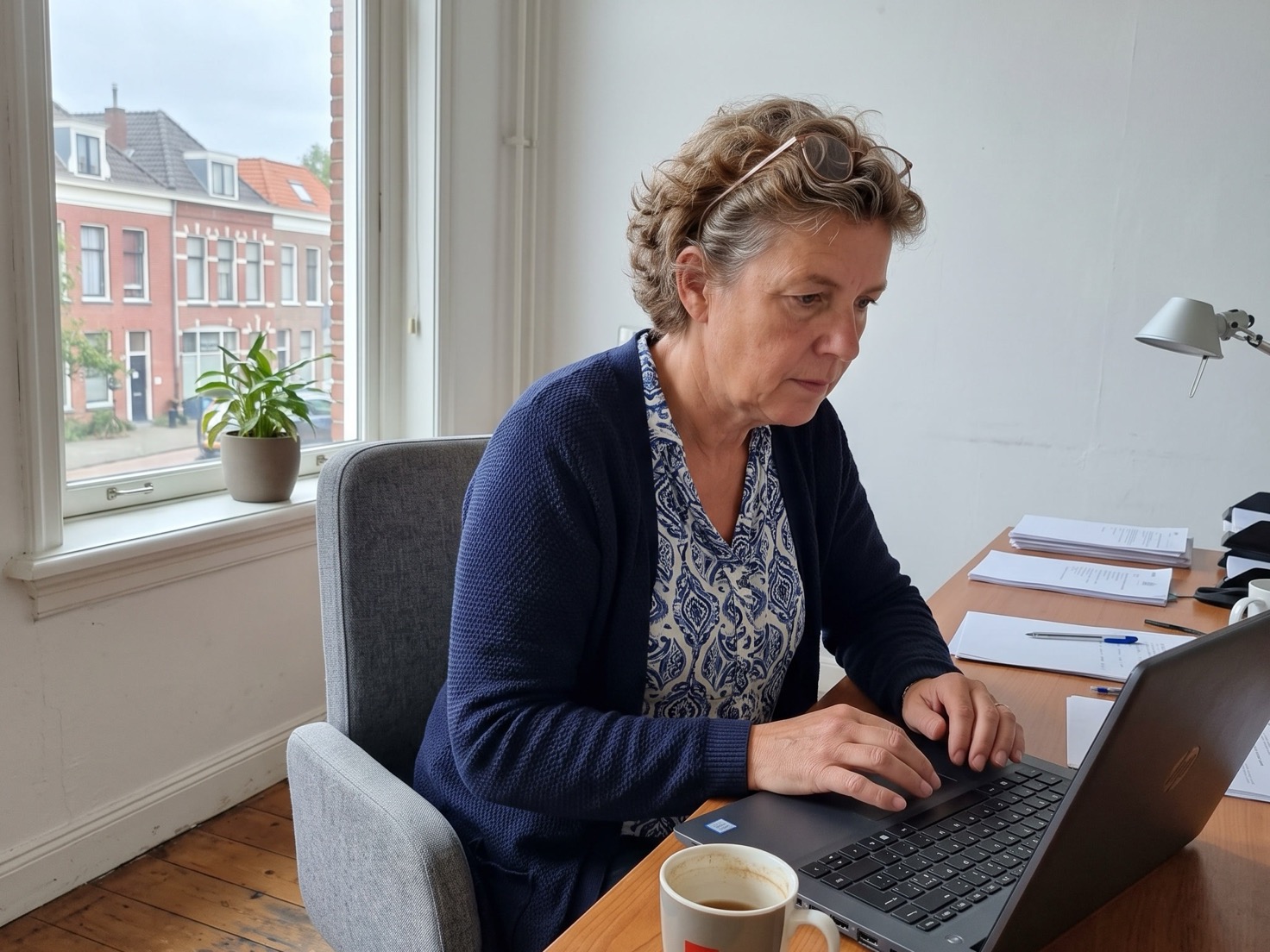 Adviseur werkt geconcentreerd aan haar bureau in een rustig advieskantoor