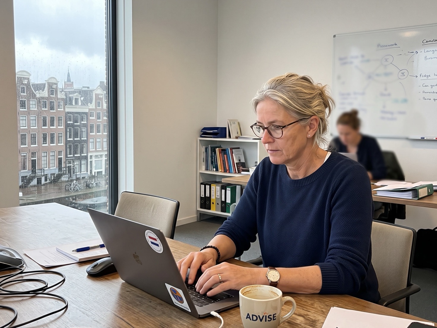 Financieel adviseur werkt aan een laptop aan een overlegtafel in een rustig advieskantoor
