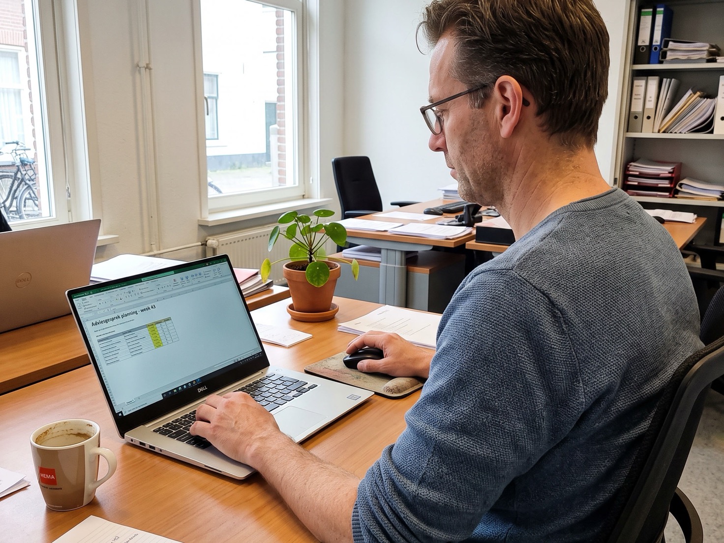 Adviseur werkt op kantoor achter een laptop met een spreadsheet open