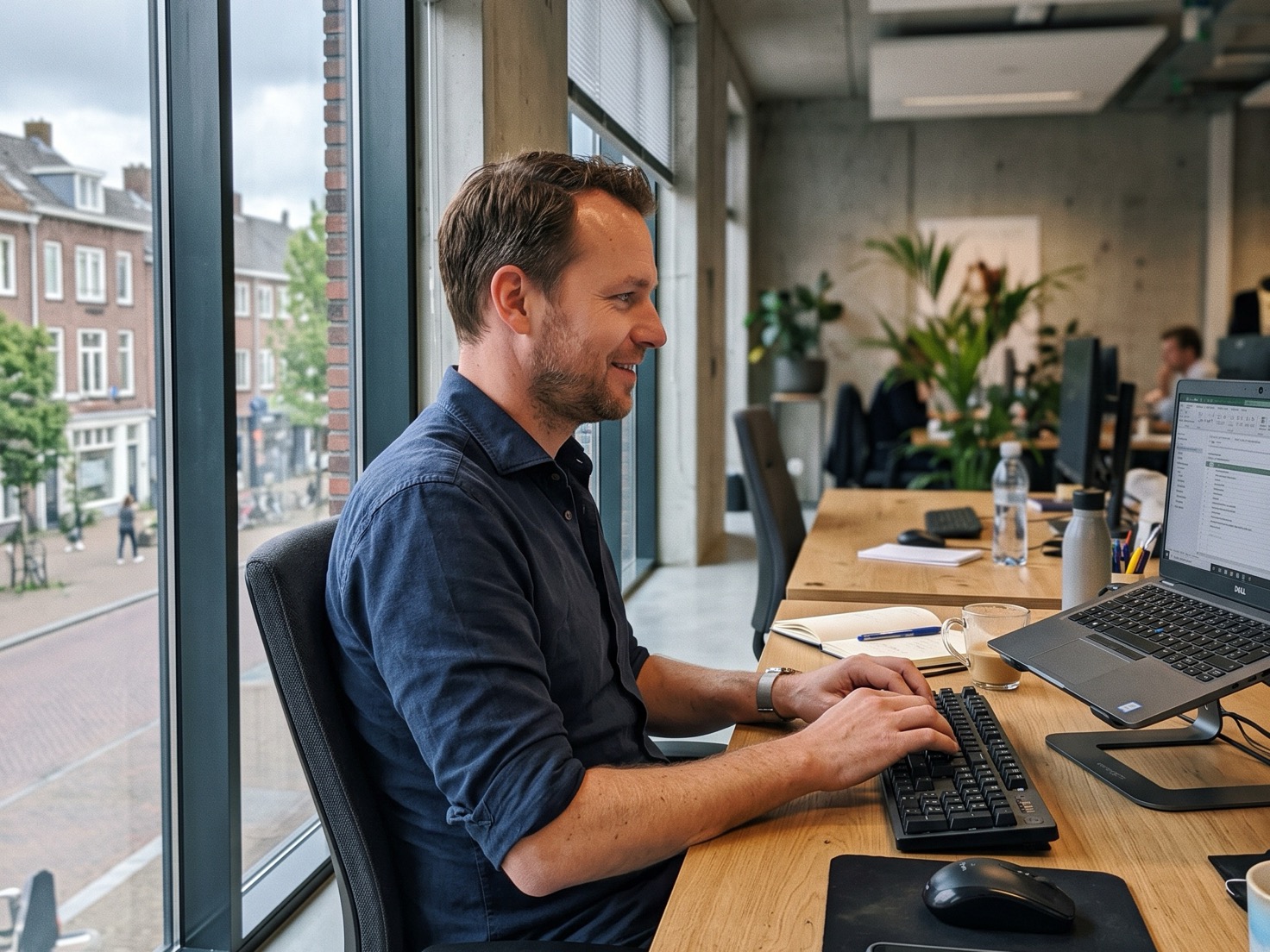 Adviseur werkt aan een computer bij het raam van een advieskantoor