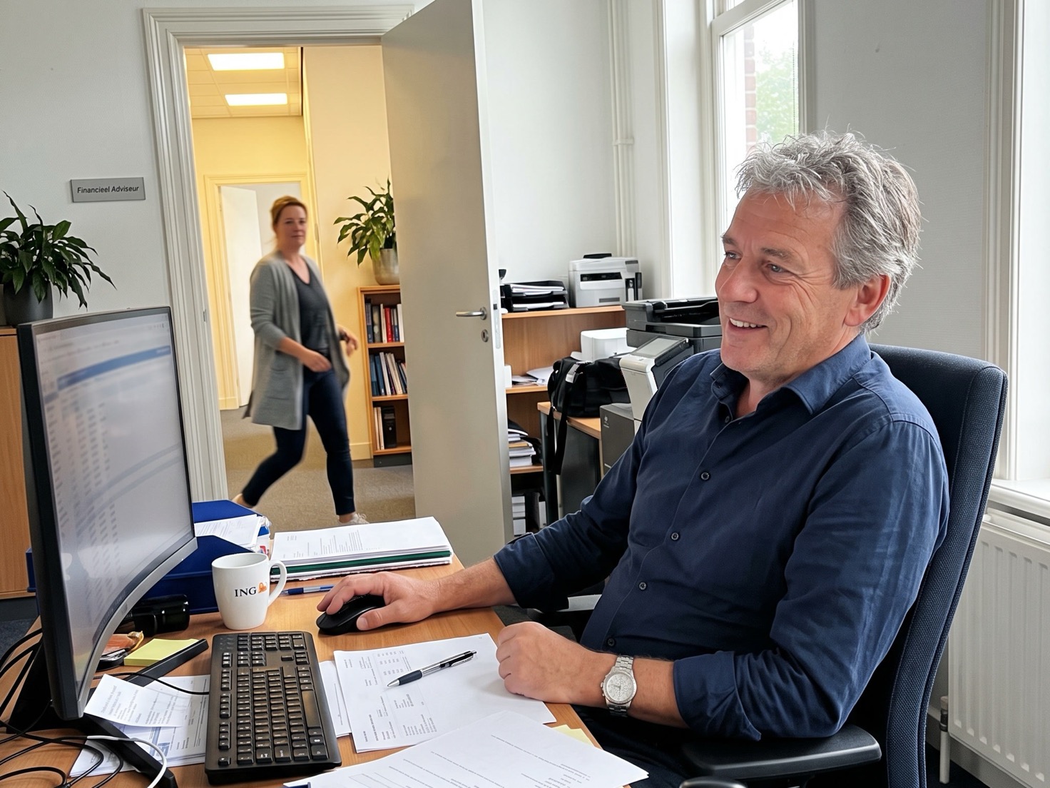 Financieel adviseur aan zijn bureau in een rustig kantoor, terwijl er iemand de deur binnenkomt