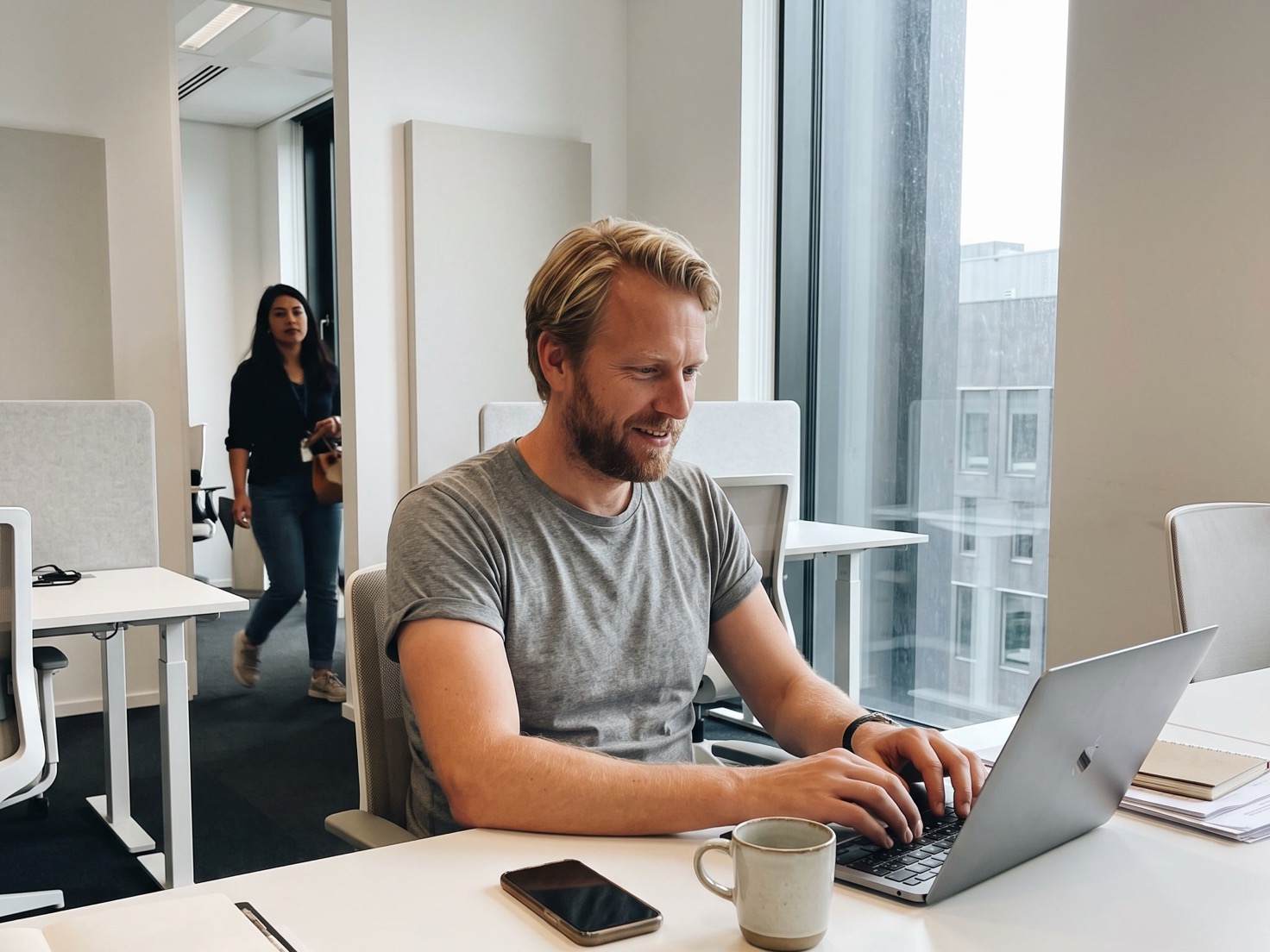 Adviseur reageert rustig op een bericht op zijn telefoon terwijl hij verder werkt op zijn laptop