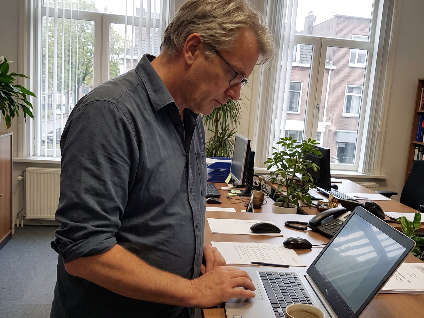 Adviseur werkt staand aan een laptop in een Nederlands advieskantoor