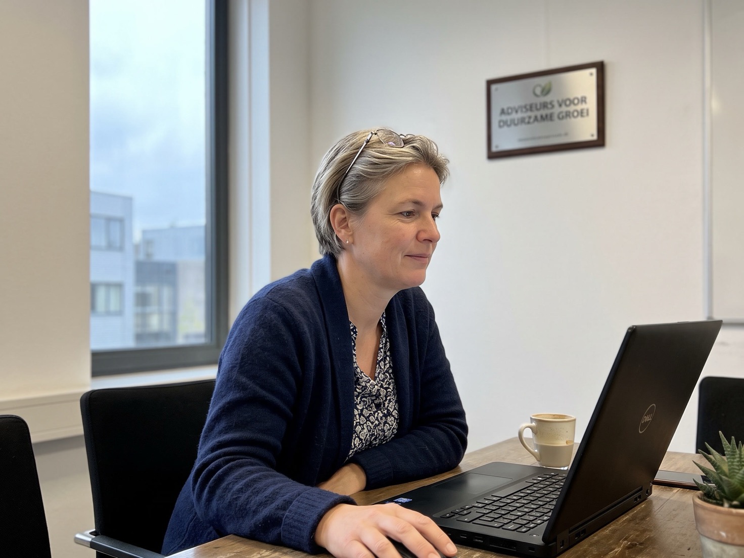 Financieel adviseur werkt geconcentreerd aan de overlegtafel, met op de achtergrond een ingelijst keurmerk aan de muur