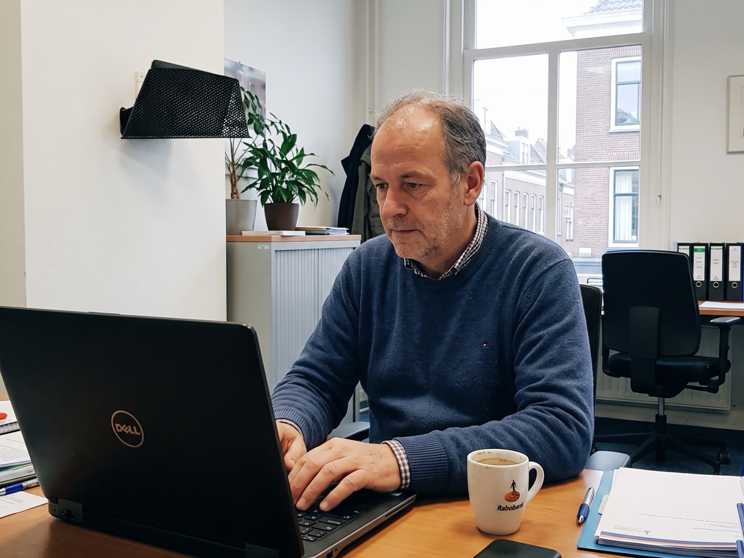 Financieel adviseur werkt geconcentreerd achter zijn laptop op kantoor, van opzij gezien