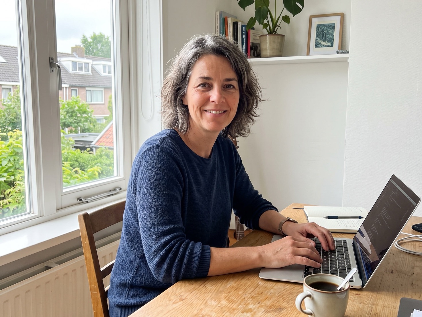Vrouw van rond de vijftig werkt geconcentreerd achter een laptop in een licht Nederlands advieskantoor