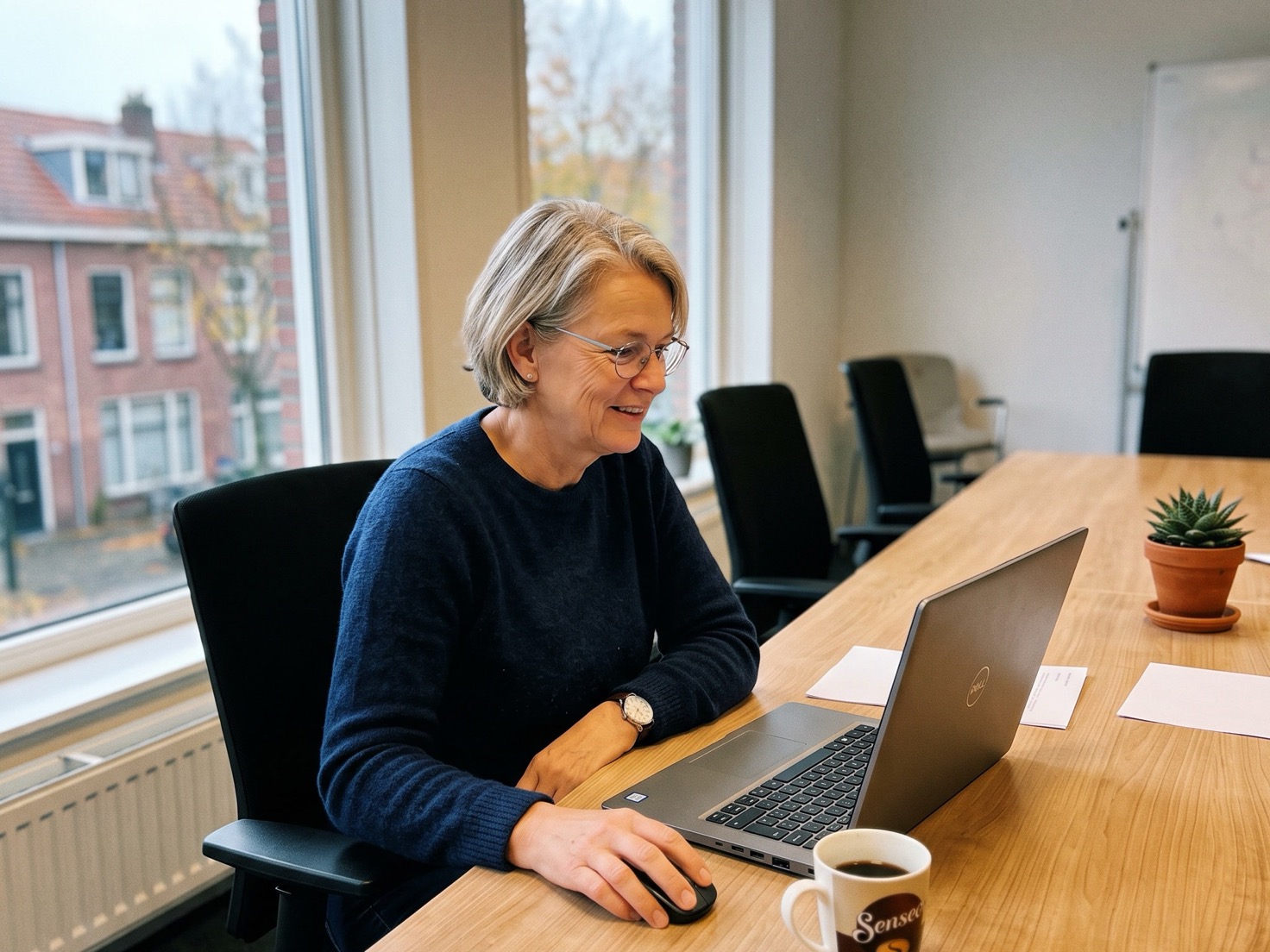 Adviseur werkt geconcentreerd aan laptop aan de overlegtafel van een advieskantoor