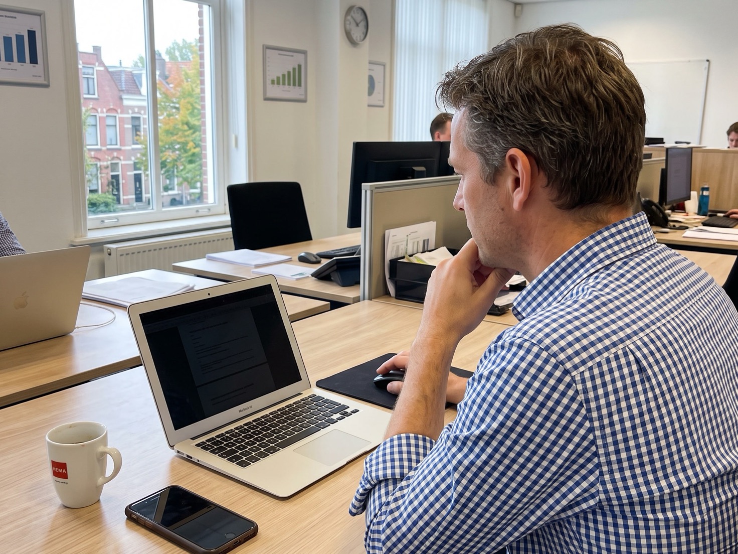 Adviseur werkt achter zijn laptop aan zijn website, gezien over de schouder