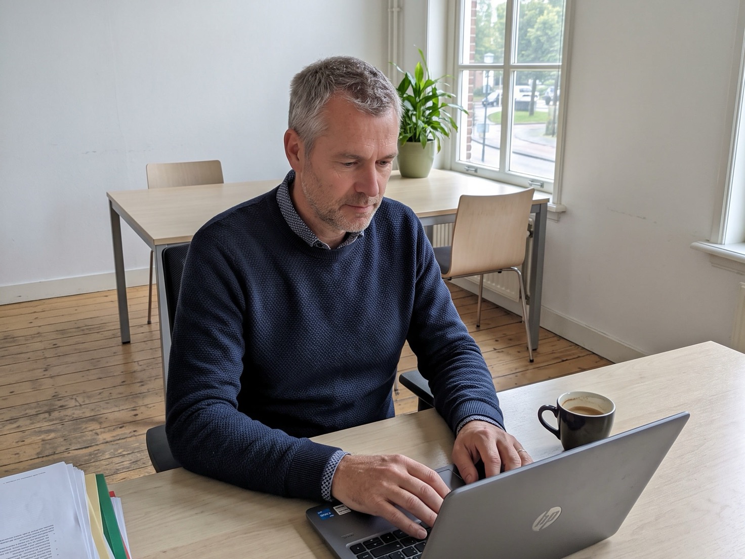 Financieel adviseur werkt geconcentreerd achter zijn bureau met het laptopscherm van de camera af
