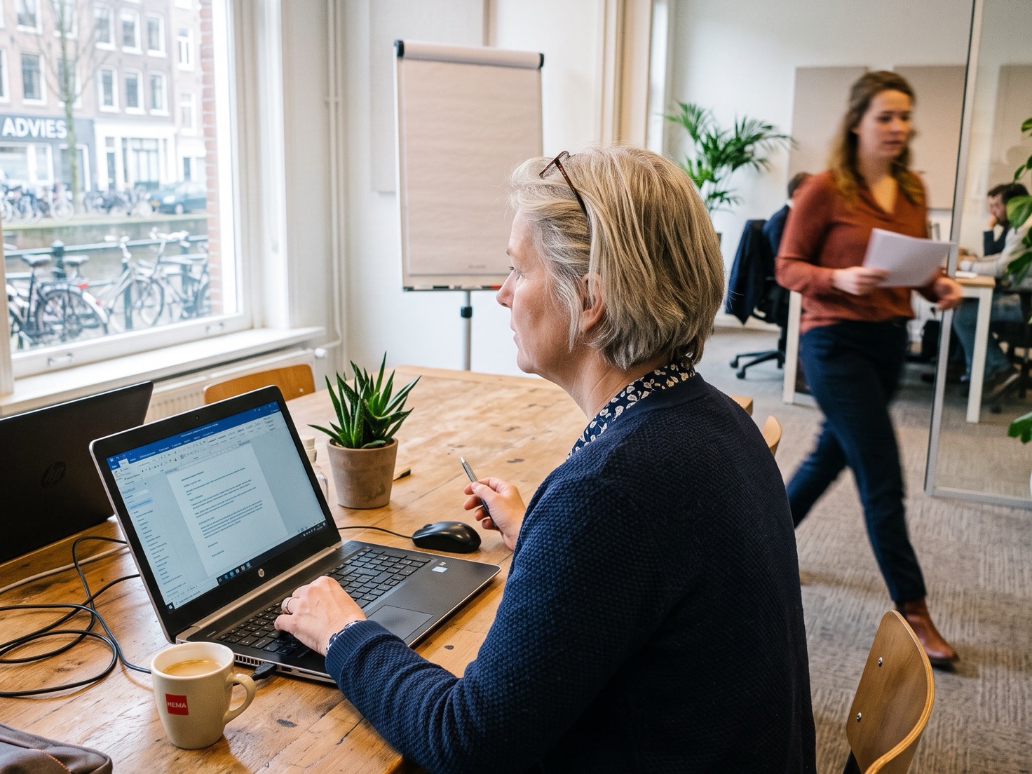 Financieel adviseur werkt geconcentreerd achter haar laptop aan een overlegtafel in een Nederlands advieskantoor