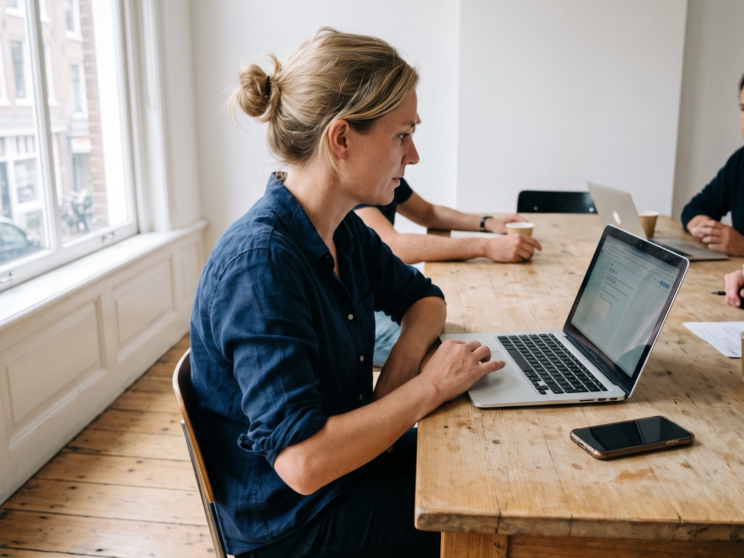 Financieel adviseur werkt aan de overlegtafel achter haar laptop in een advieskantoor