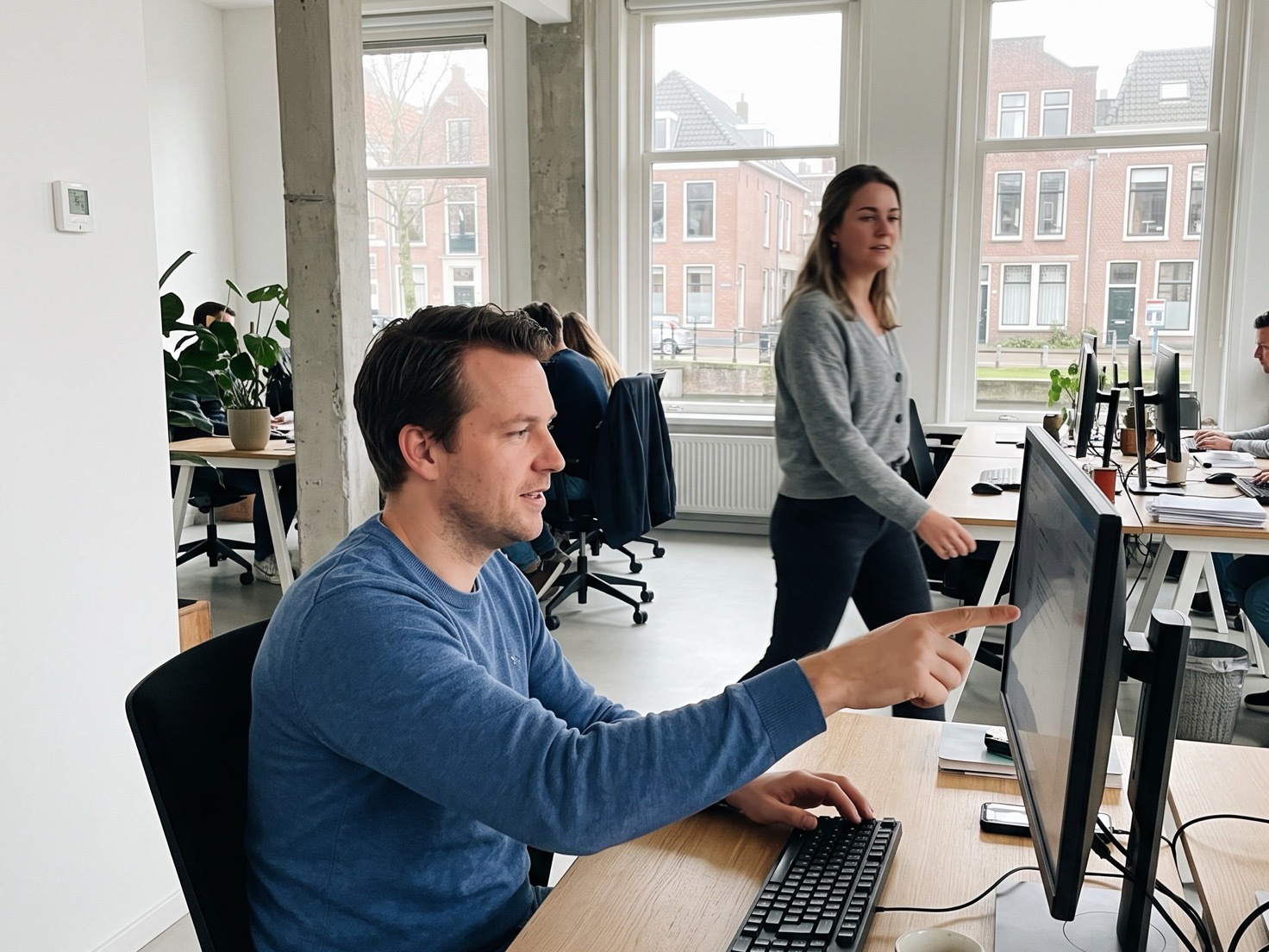 Financieel adviseur die op zijn beeldscherm wijst terwijl een collega meekijkt
