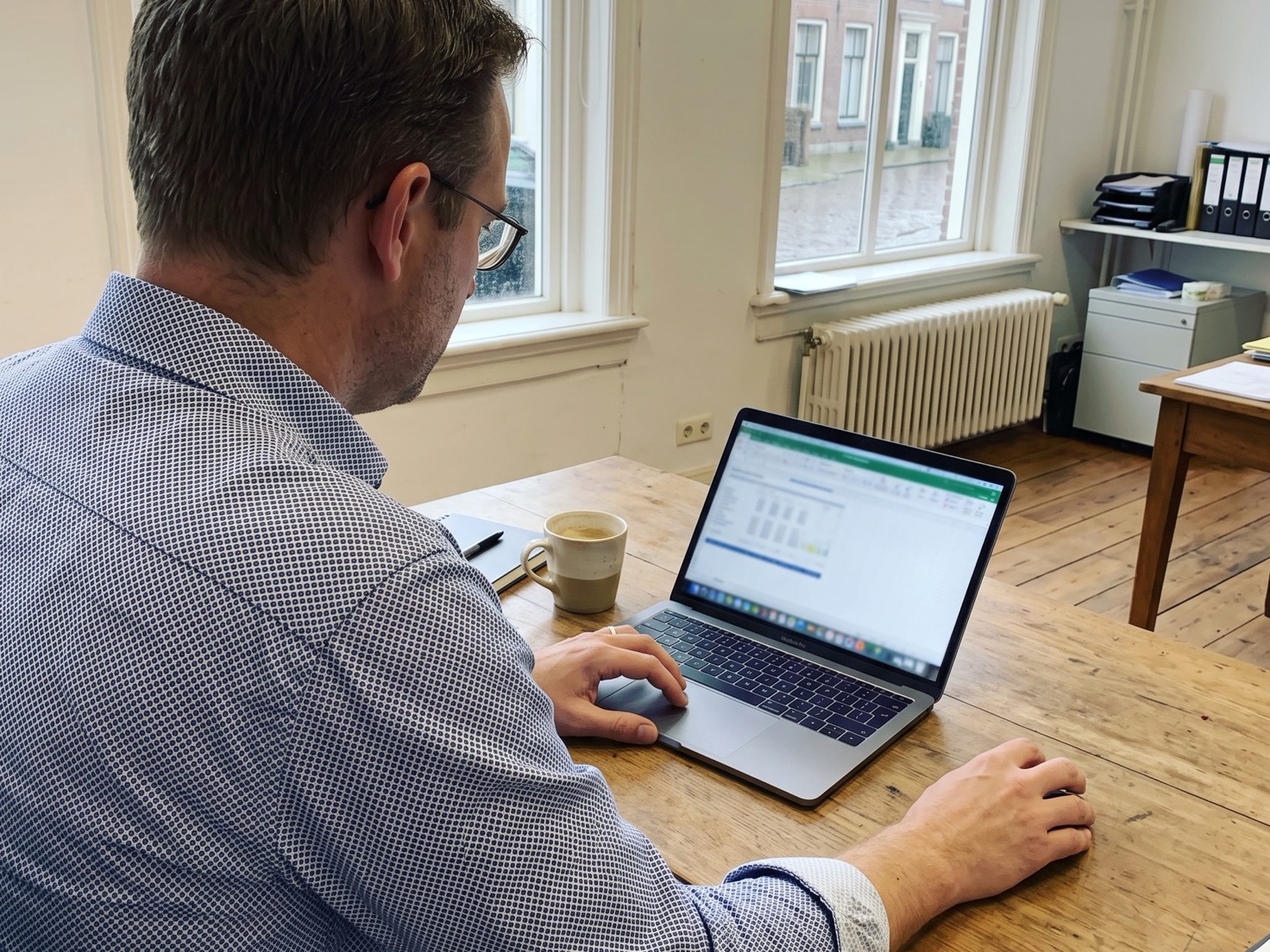 Financieel adviseur werkt achter zijn laptop in een rustig advieskantoor