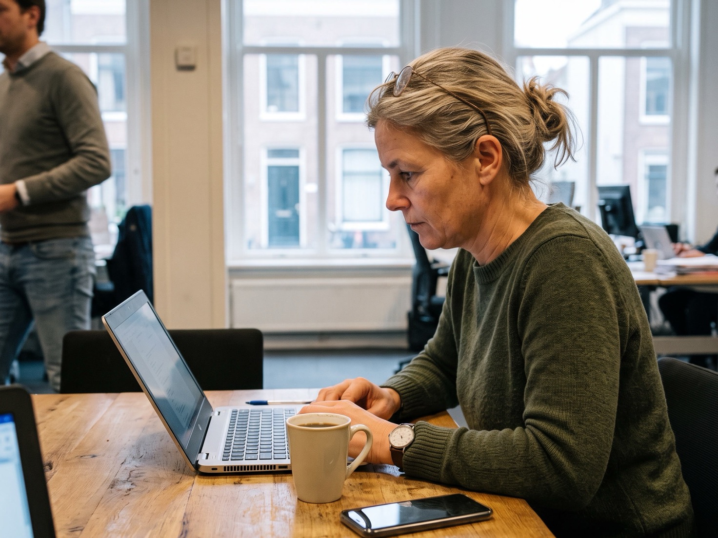 Adviseur werkt geconcentreerd achter haar laptop aan de overlegtafel van een rustig advieskantoor