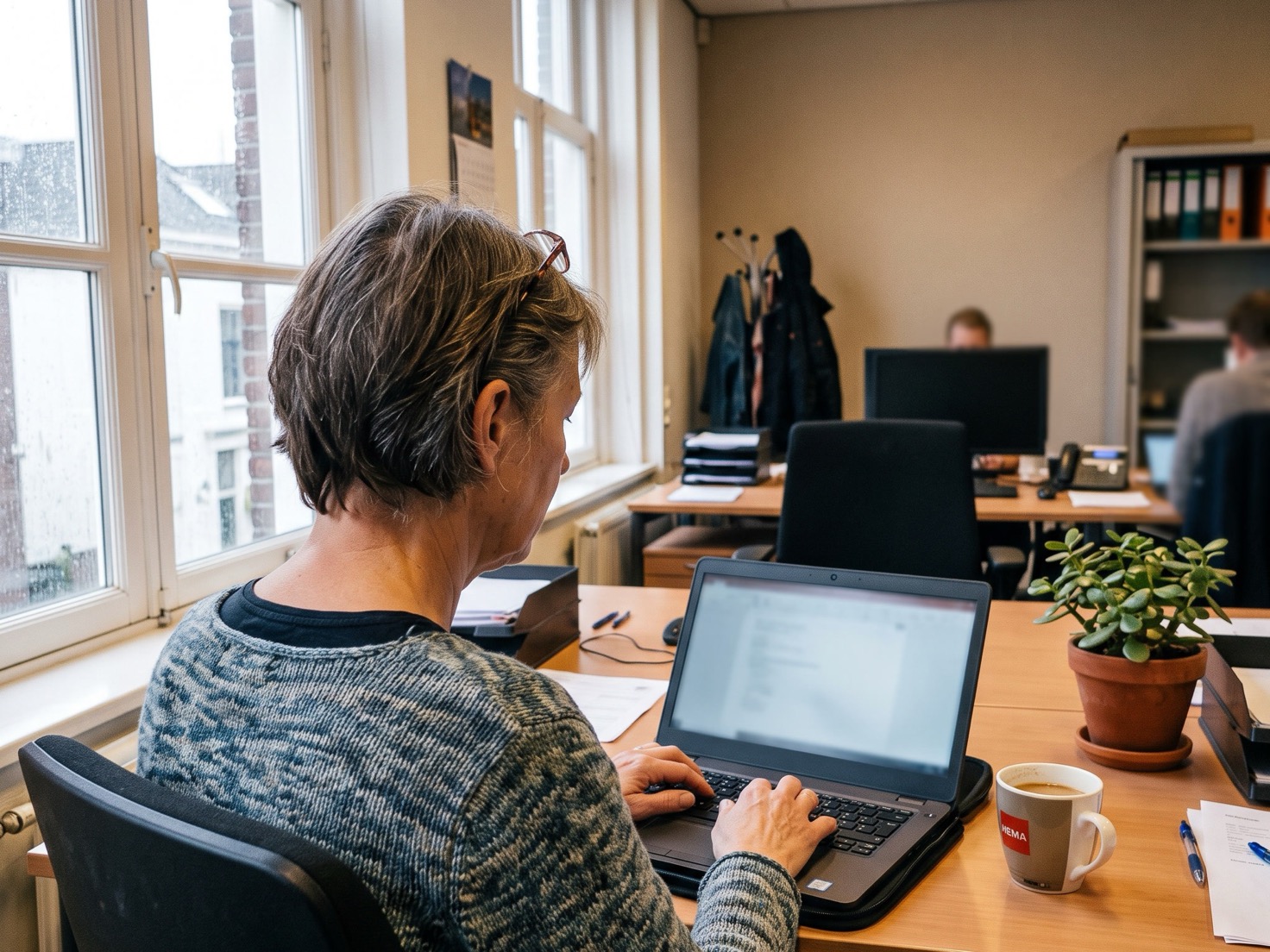 Adviseur werkt rustig achter haar laptop in een Nederlands advieskantoor