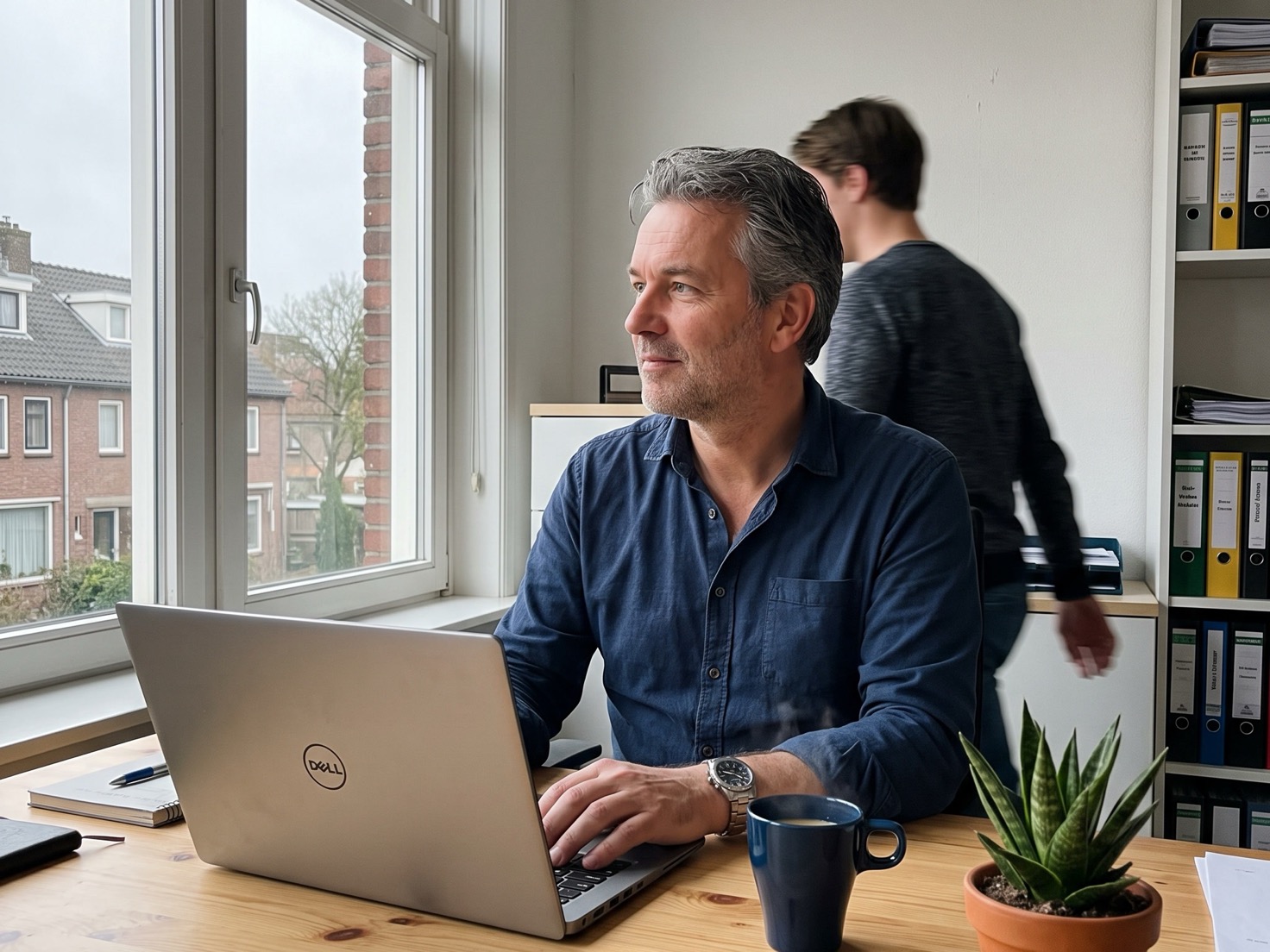 Financieel adviseur achter zijn bureau terwijl een collega langsloopt voor de overdracht