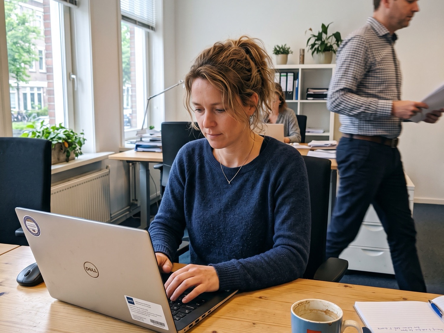 Adviseur typt achter een houten bureau in een rustig advieskantoor