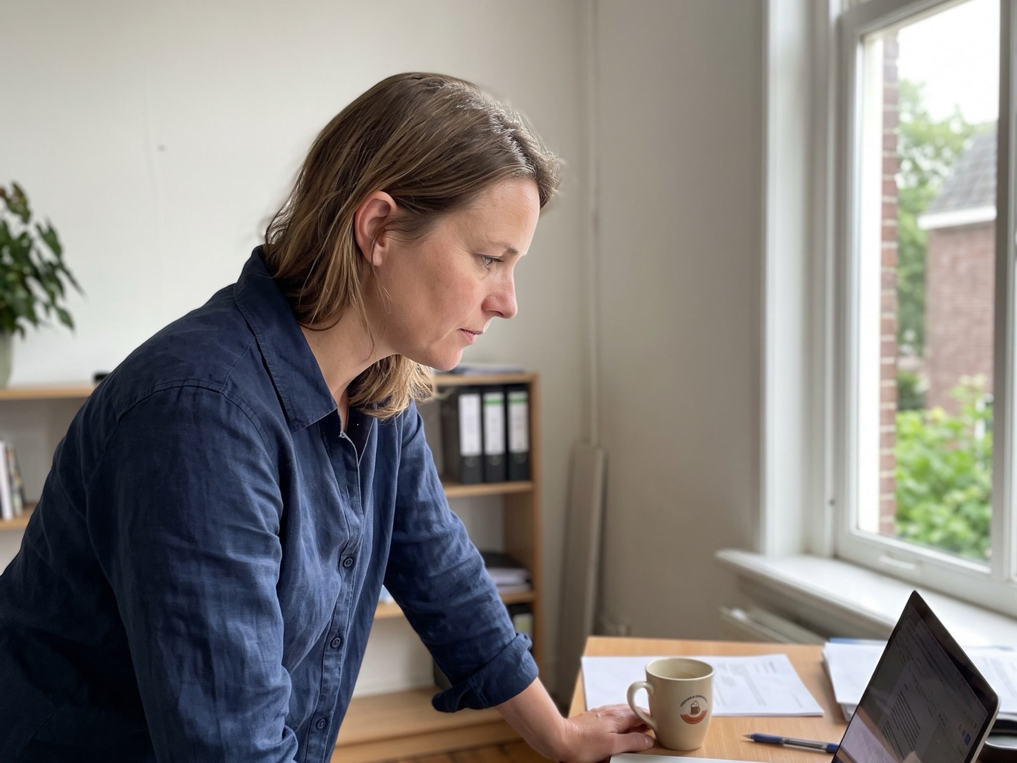 Financieel adviseur buigt zich over een laptop aan het bureau in een rustig advieskantoor