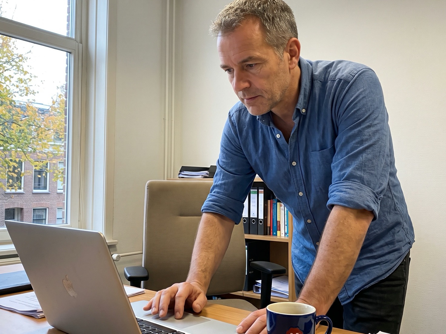 Financieel adviseur die naast zijn bureau een update op zijn laptop installeert