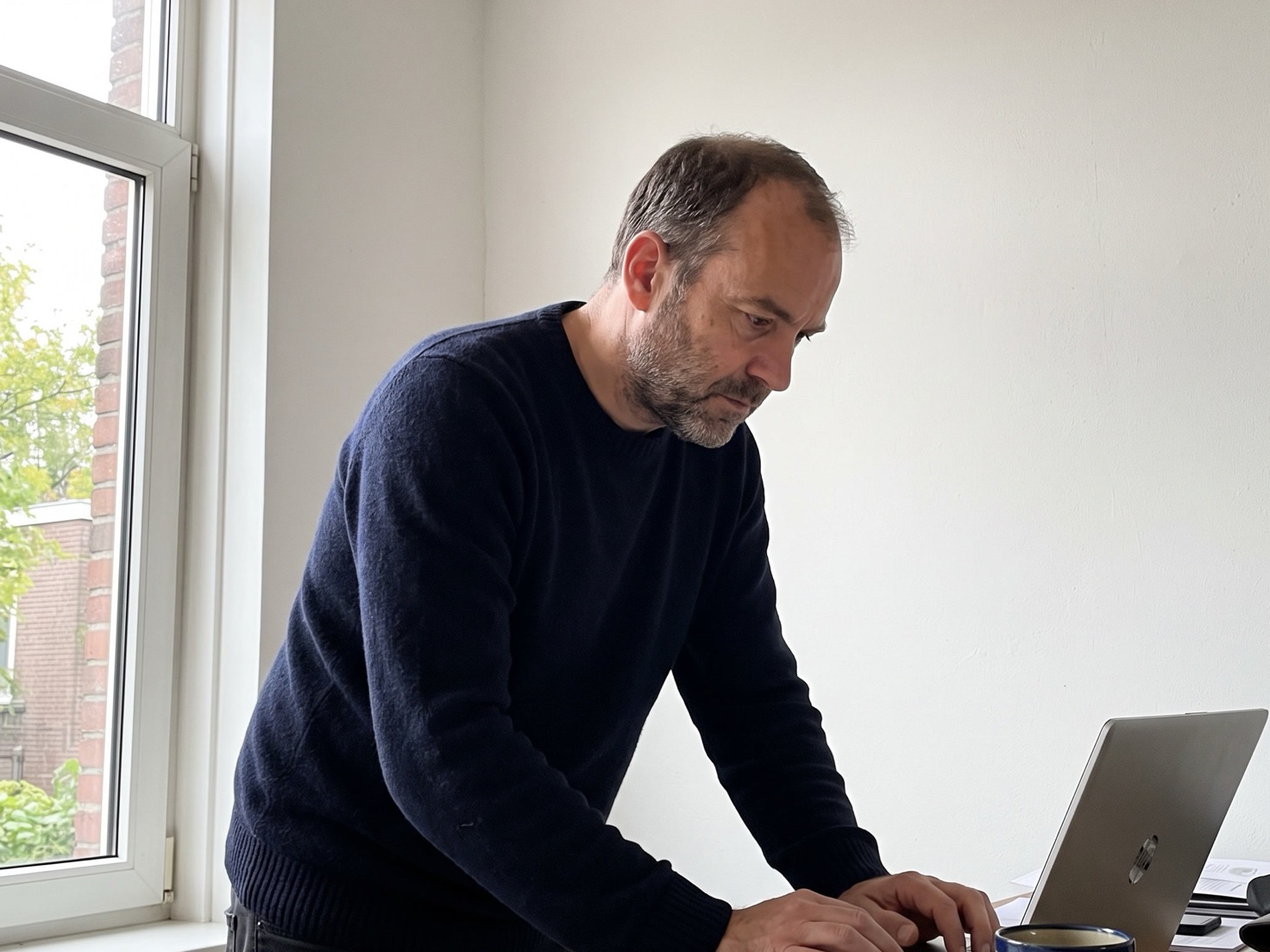 Financieel adviseur werkt staand aan een laptop in zijn advieskantoor